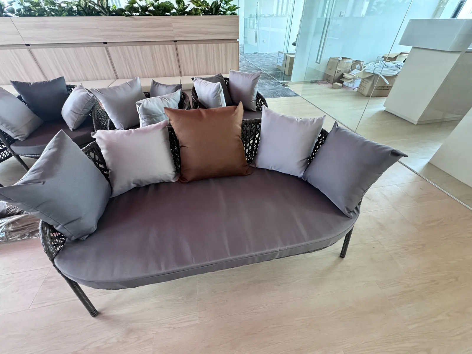 Curved woven outdoor daybed with coordinated cushions in an office lounge