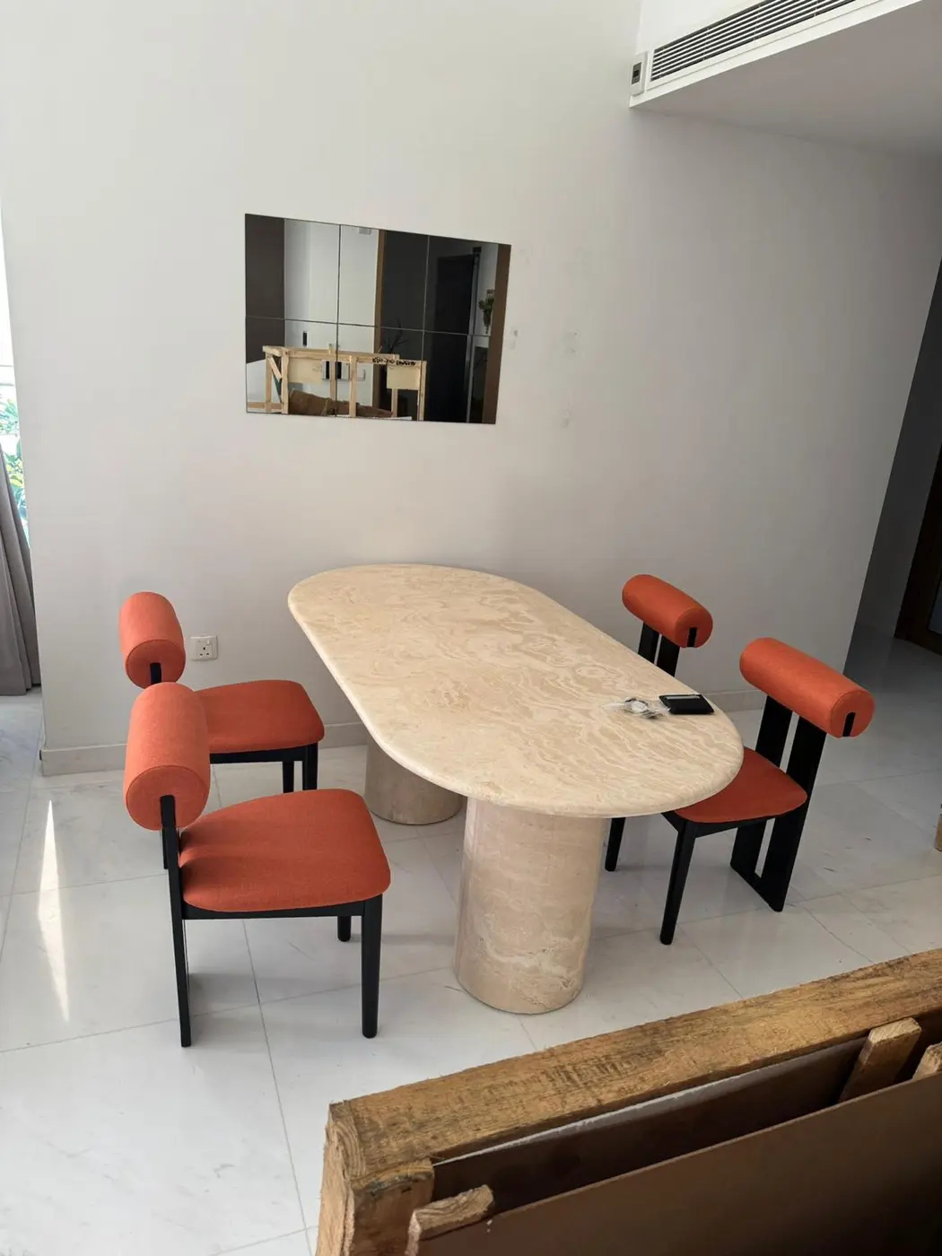 Stone dining table with orange upholstered chairs