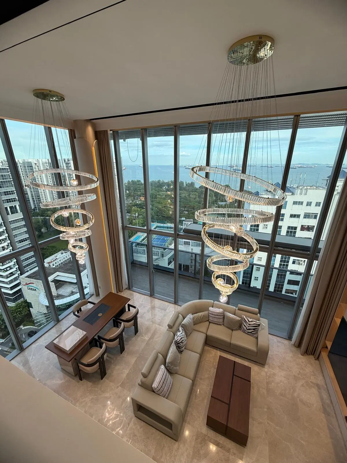 Dramatic double-height living room with paired crystal pendant lights and ocean view