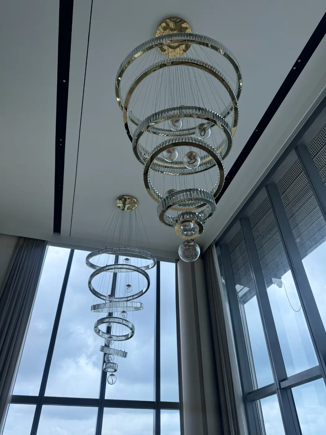 Sculptural crystal ring pendant lights installed in a double-height home