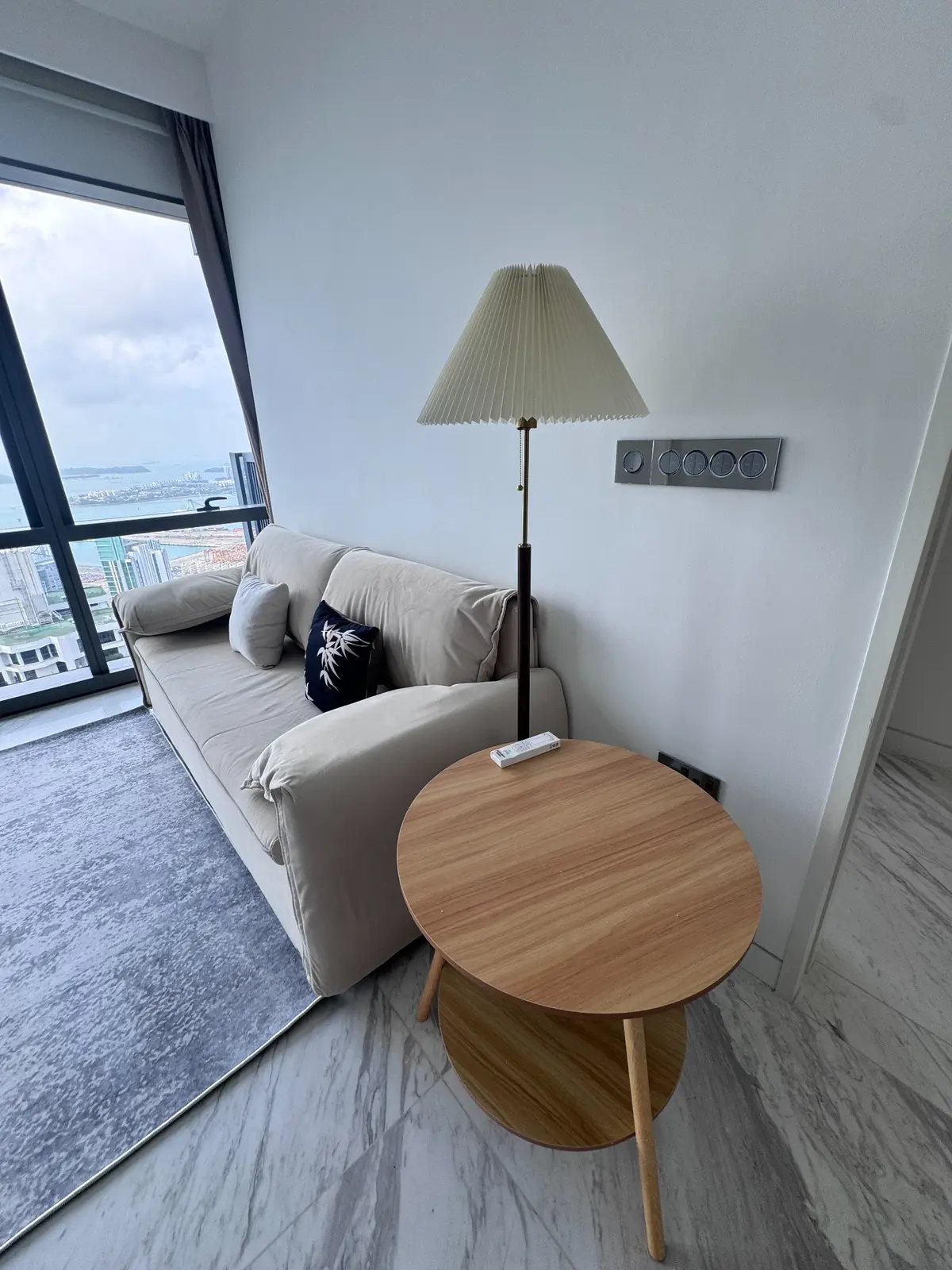 Timber side table and floor lamp beside a soft upholstered sofa