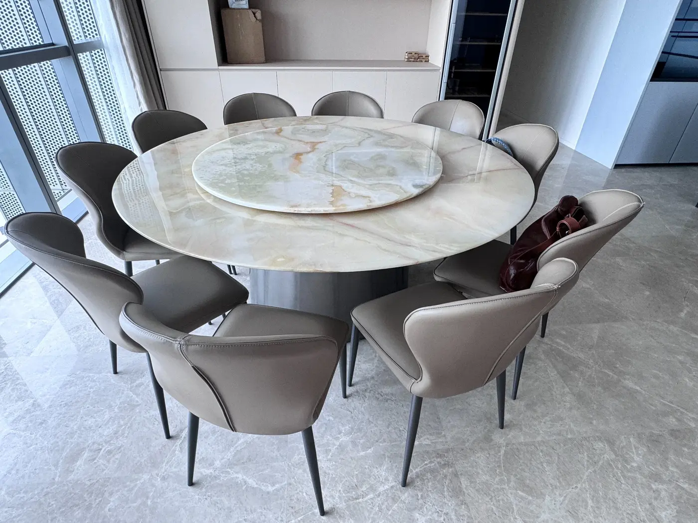 Large round stone dining table with lazy Susan and upholstered chairs
