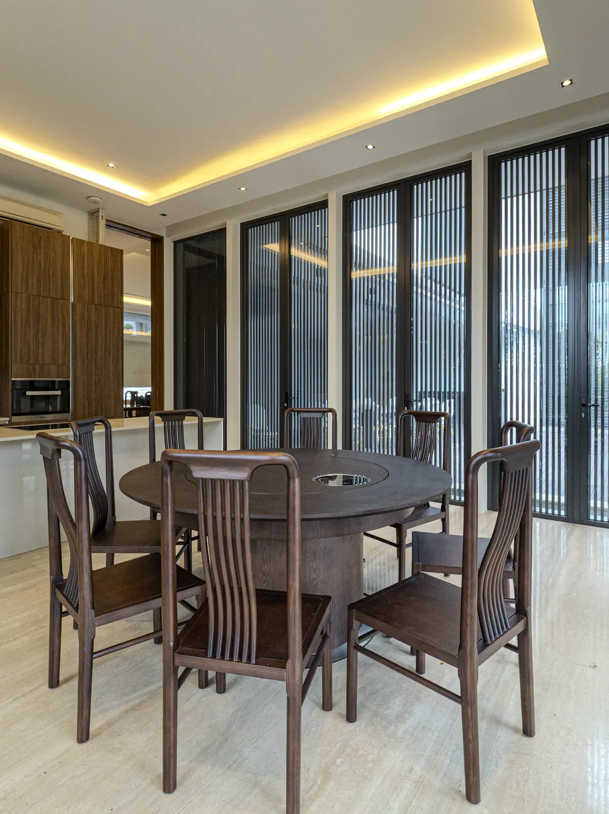 Round timber dining table beside full-height windows